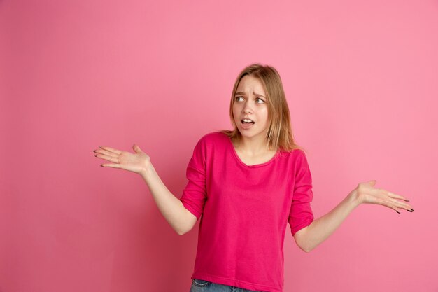 Geschokt, onzeker. Portret van de blanke jonge vrouw geïsoleerd op roze muur, zwart-wit. Mooi vrouwelijk model.