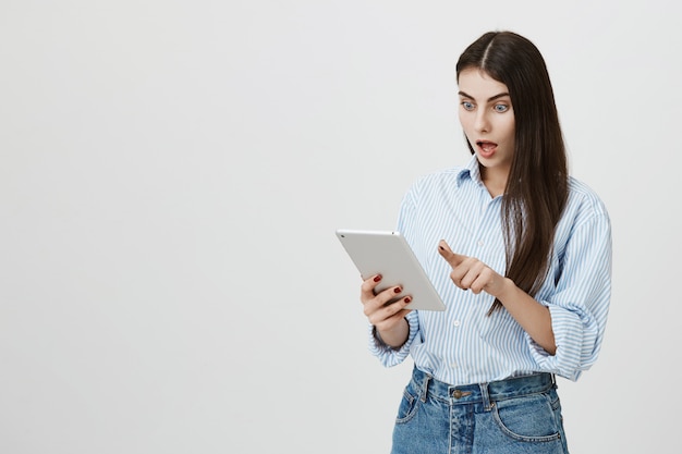 Geschokt vrouw opgewonden staren naar digitale tablet-display