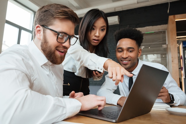 Geschokte Aziatische vrouw die vertoning van laptop computer toont aan haar collega's