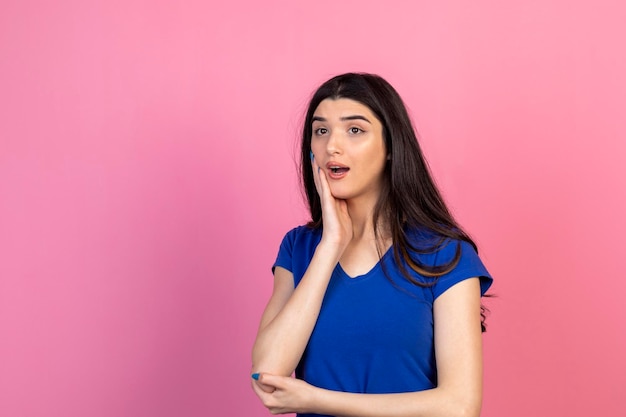 Geschokte jonge vrouw die haar hand voor haar gezicht houdt en opzij kijkt met open mond Foto van hoge kwaliteit