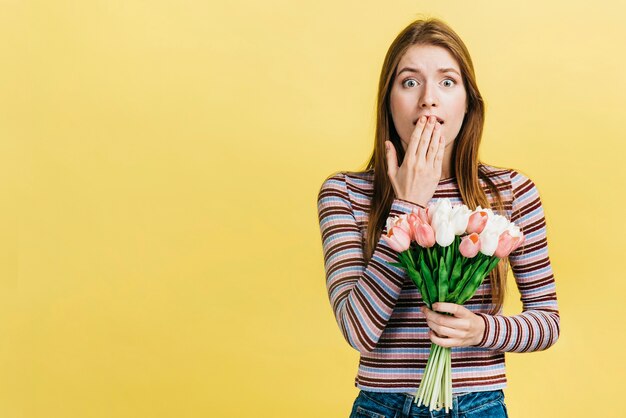 Geschokte vrouw die een boeket van tulpen houdt
