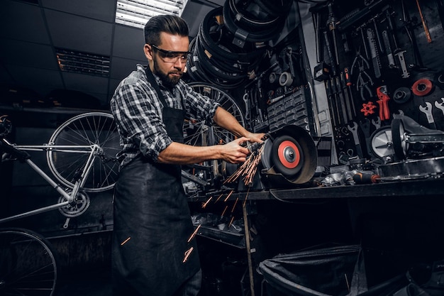 Geschoolde reparateur werkt met werktuigmachines in drukke bucycle-werkplaats.