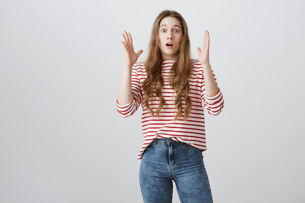 Geschrokken en geschokt meisje hief haar handen op, hijgend van verbazing