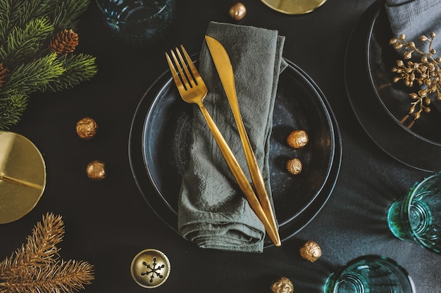 Geserveerde kersttafel in donkere tinten met gouden deco.