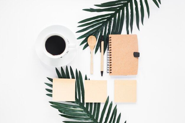 Gesloten dagboek; koffiekop; zelfklevende notitie; lepel en pen met koffiekopje op witte achtergrond
