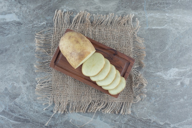 Gesneden aardappel op een schaal, op de onderzetter, op de marmeren tafel.