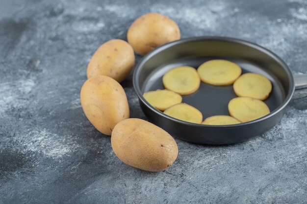 Gesneden aardappelen binnenkant van pan op grijze achtergrond. Hoge kwaliteit foto