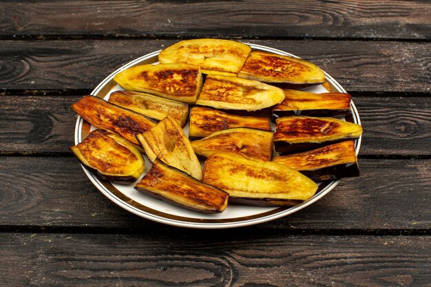 Gesneden aubergines gebakken lekker op een ronde plaat en rustieke houten bureau