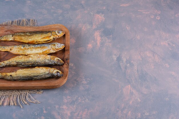Gesneden citroenen en gezouten vis op een snijplank op een jute servet, op het marmeren oppervlak
