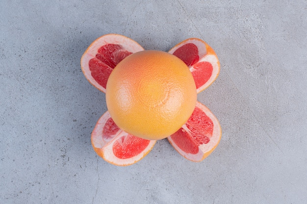 Gratis foto gesneden en hele grapefruits weergegeven op marmeren achtergrond.