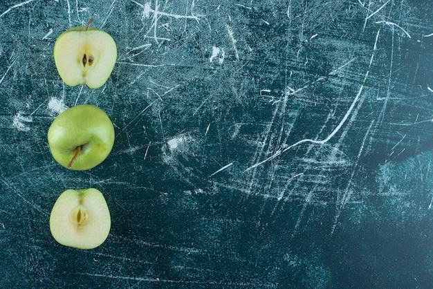 Gesneden en hele groene appels op marmeren tafel.