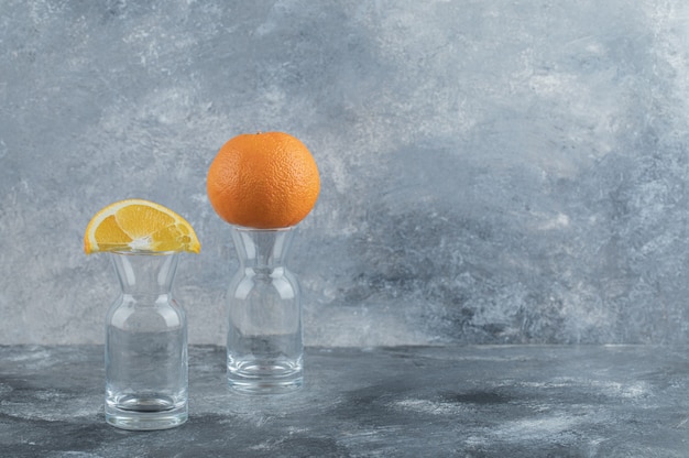 Gesneden en hele sinaasappel bovenop leeg glas.