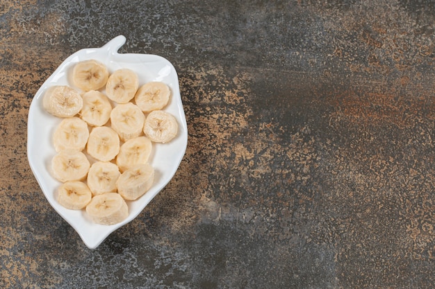 Gratis foto gesneden gepelde bananen op witte plaat.