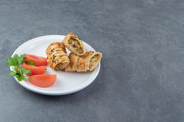 Gesneden gevlochten broodje gevuld met vlees op witte plaat.