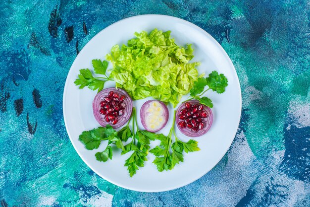 Gesneden groene groenten en granaatappelpitjes op een bord