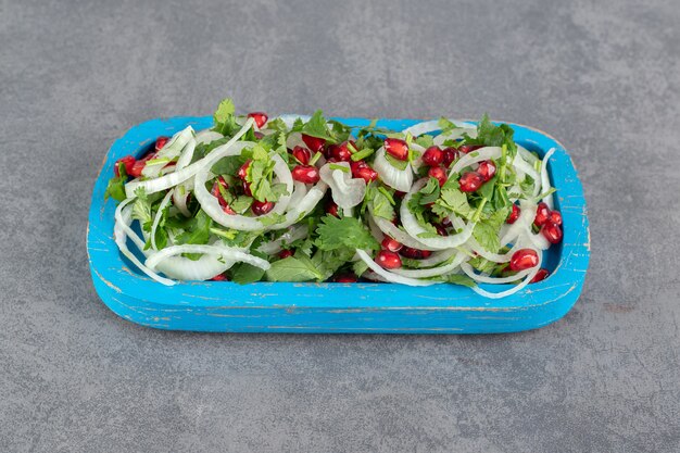 Gesneden Groenen, uien en granaatappelzaden op blauw bord. Hoge kwaliteit foto
