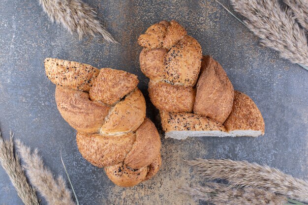 Gesneden helften van strucia brood en bundel van tarwe stengels op marmeren oppervlak