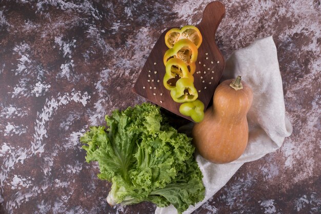 Gesneden pompoen, paprika en sla op marmer