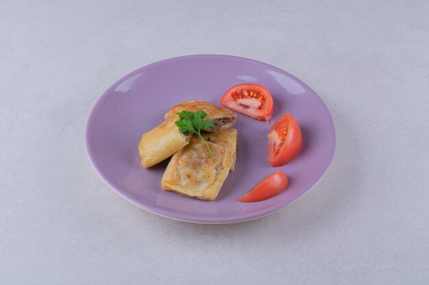 Gesneden tomaten en pannenkoek met vlees op plaat op het donkere oppervlak
