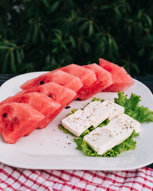 Gesneden watermeloen met witte kaas en slablad.