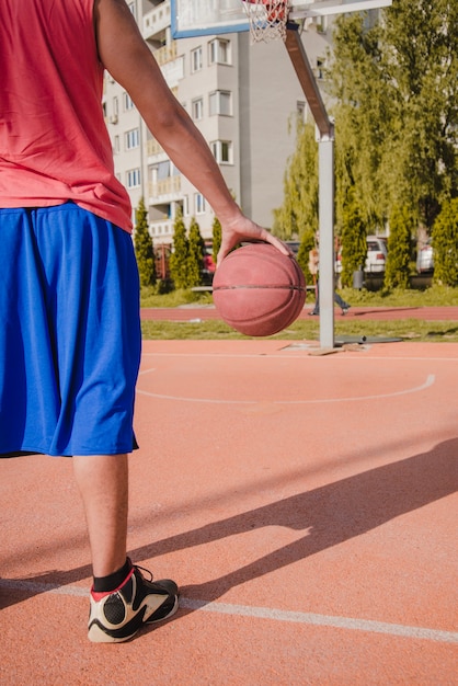 Gesneden weergave basketbal speler bedrijf bal met de hand