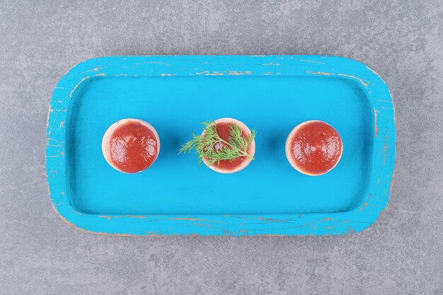 Gesneden worstjes met ketchup op blauwe houten bord