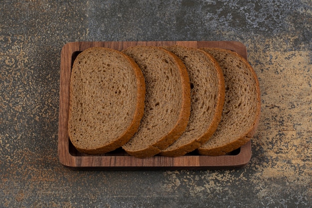 Gesneden zwart brood op houten plaat