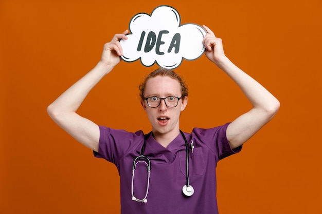 gespannen bedrijf idee zeepbel jonge mannelijke arts dragen uniform met stethoscoop geïsoleerd op oranje background