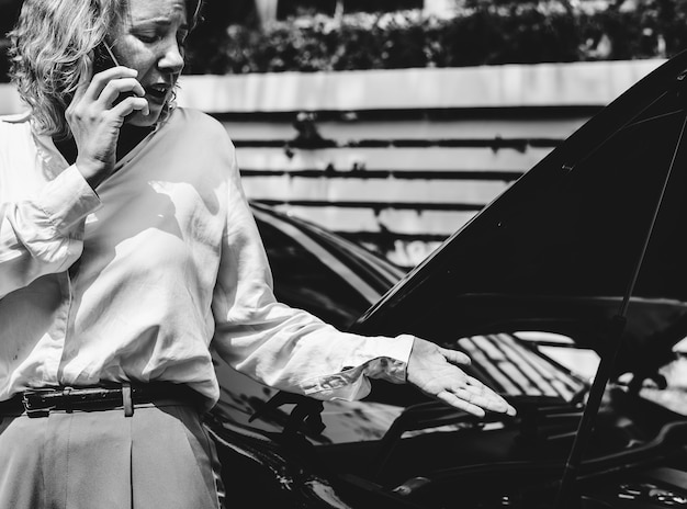 Gratis foto gespannen vrouw op afroep over haar auto