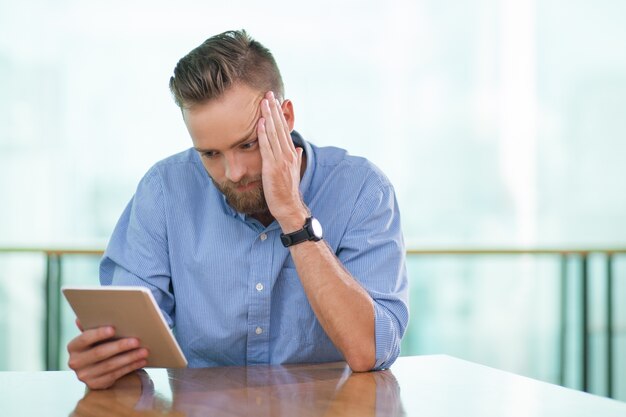 Gespannen Zitting van de mens in Cafe Tafel en Tablet met behulp van