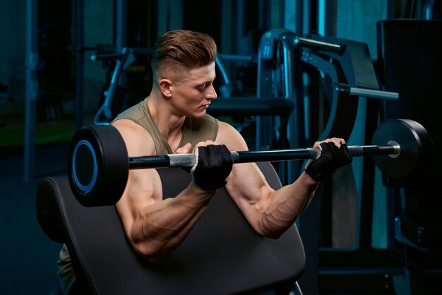 Gespierde sportman die biceps bouwt met barbell