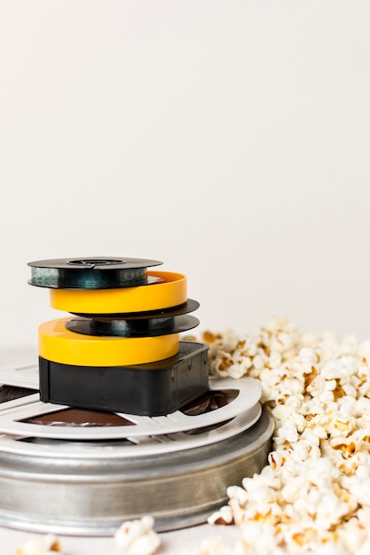 Gratis foto gestapeld van filmhaspels met popcorns tegen witte achtergrond