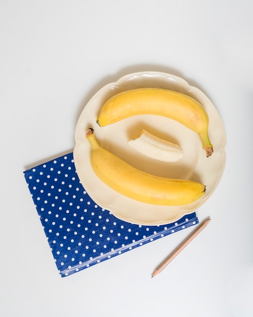 Gestippeld notitieboekje met bananen op plaat