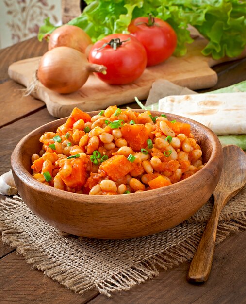 Gestoofde witte bonen en gesneden pompoen in tomatensaus