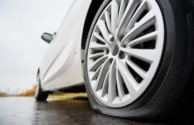 Gratis foto gestopte witte auto met lekke autoband langs de weg