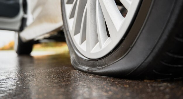 Gestopte witte auto met lekke band langs de weg