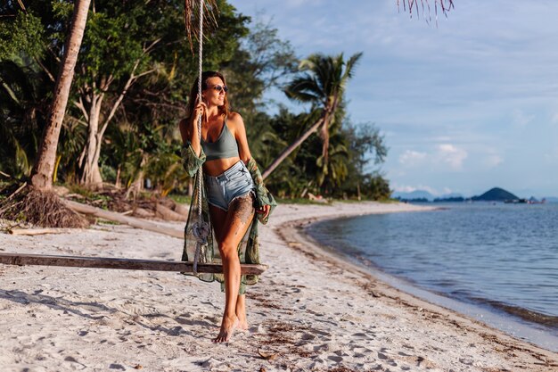 getatoeëerde blanke vrouw in denim shorts en groene trendy crop top