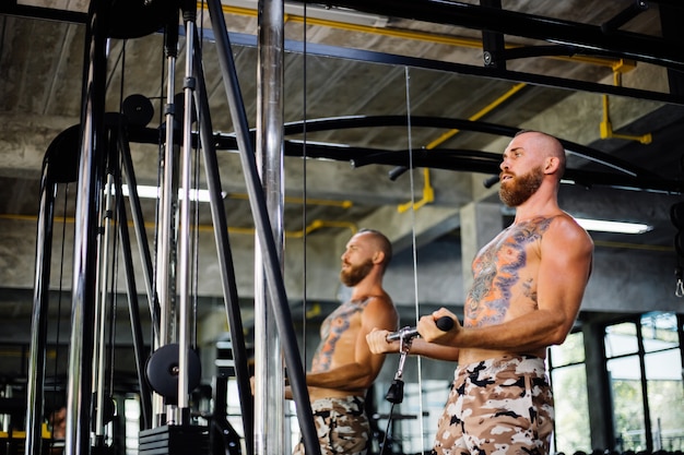 Getatoeëerde fit man doen oefening in de sportschool