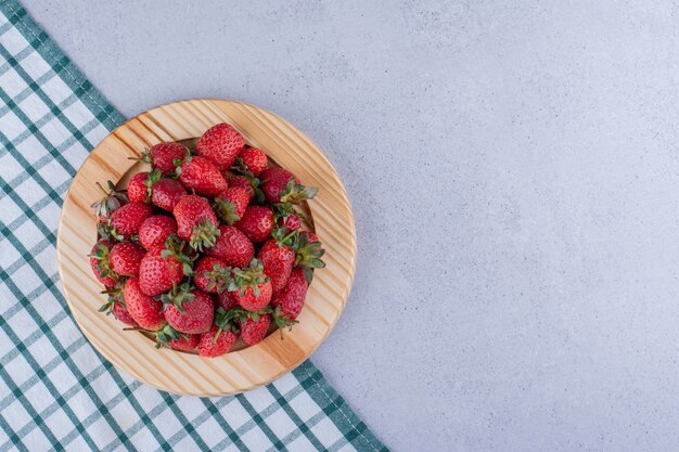 Gevouwen tafelkleed onder een schotel met een stapel aardbeien op marmeren achtergrond. Hoge kwaliteit foto