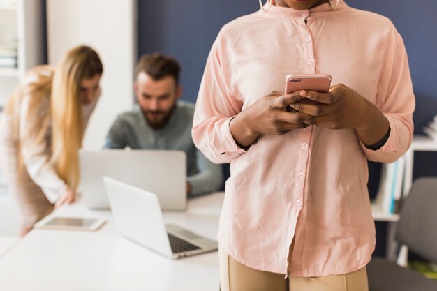 Gewasvrouw die smartphone in bureau gebruiken