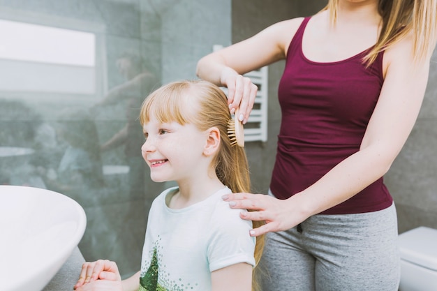 Gratis foto gewasvrouw die vrolijk meisje borstelt