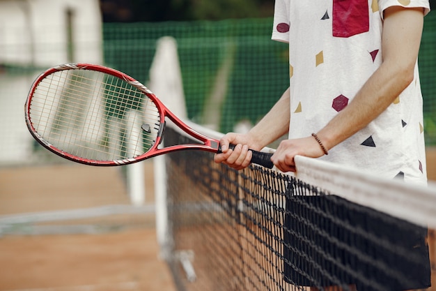 Geweldige dag om te spelen! Vrolijke jonge man in t-shirt. Guy met tennisracket en bal.