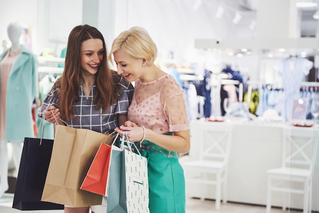 Gratis foto geweldige dag om te winkelen. twee mooie vrouwen kijken naar de tas en scheppen op over wat ze hebben gekocht