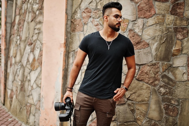 Gratis foto geweldige mooie lange arabische baard macho man fotograaf in glazen en zwarte t-shirt met professionele camera bij de hand