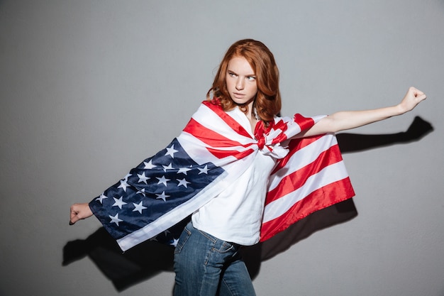 Geweldige roodharige jonge dame superheld met Amerikaanse vlag