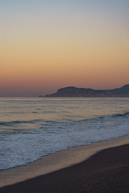 Geweldige strandzonsondergang met eindeloze horizon en eenzame bergenfiguren in de verte