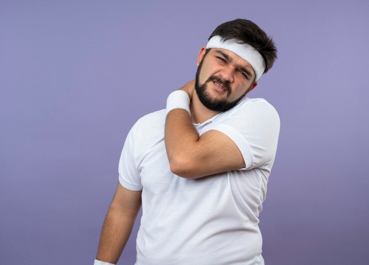 Gratis Foto gewonde jonge sportieve man met hoofdband en polsband greep pijnlijke schouder