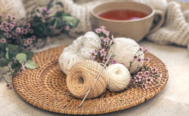 Gratis foto gezellige compositie met breigarens een kopje thee en bloemen