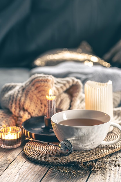 Gratis foto gezellige huiscompositie met een kopje thee kaarsen en een gebreide element