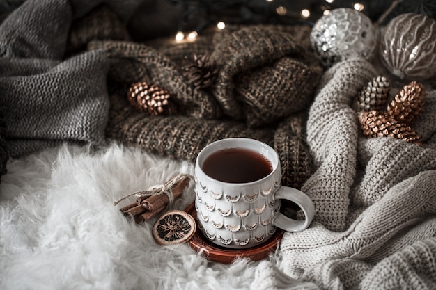 Gezellige kerstochtend met kopje thee in bed. Stillevenscène met truien. Dampende kop warme koffie, thee. Kerst concept.